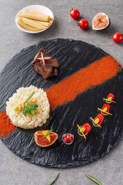 Reis, Brokkoli, Feigen und gebratenes Fleisch auf schwarzem Teller mit Hühneraugen und Kirschtomaten — Stockfoto