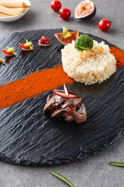 Enfoque selectivo de arroz, brócoli, higo y carne frita en plato negro con callos y tomates cherry - foto de stock