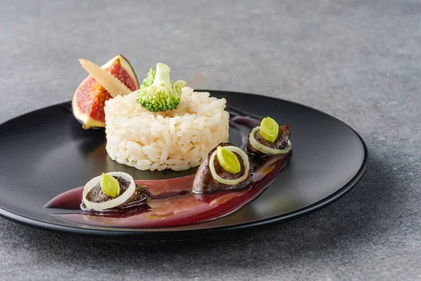 Arroz, brócolis, figo e carne frita com molho na placa preta e superfície de pedra — Fotografia de Stock