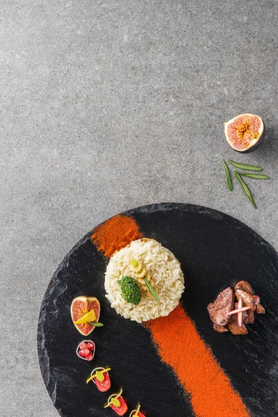 Top view of rice, broccoli, fig and fried meat with sauce on black plate — Stock Photo