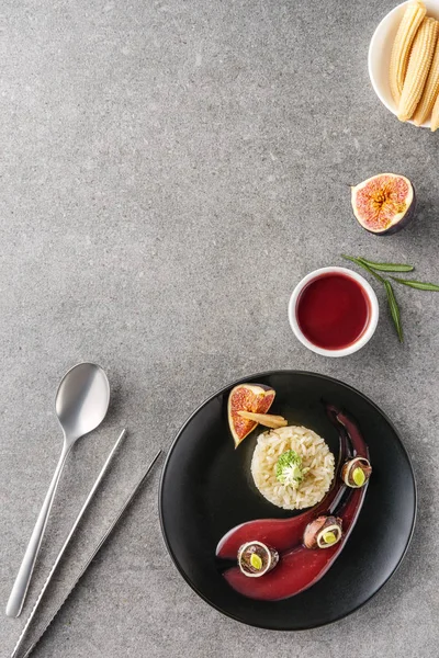 Top view of rice, broccoli, fig and fried meat with sauce on black plates with corns — Stock Photo