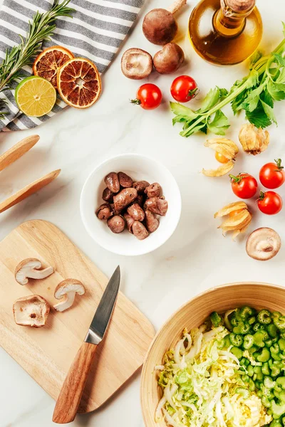 Funghi sul tagliere con cavolo e sedano in piatto con olio, pomodorini, lime — Foto stock