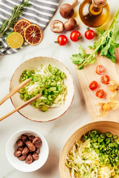 Pomodorini ciliegini sul tagliere con cavolo e sedano in piatti con olio, lime e verde — Foto stock