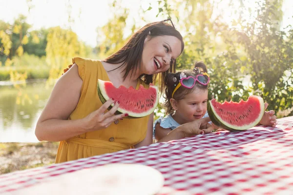 Anne ve kızı piknikte karpuz dilimi yiyor