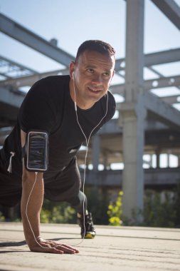 Bir sporcu rustik, bitmemiş binada egzersizleri itmek çalışır. Sporcuya ve büyük beton sütunlara düşük bakış açısı.