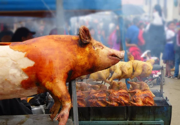 Big roasted pig and whole chickens are on the sale at the opened market in Cuenca. Traditional food in Ecuador