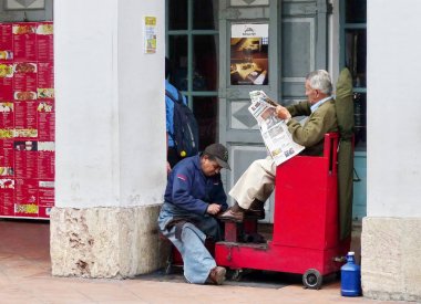 Cuenca, Ekvador - 8 Mart 2019: Park Calderon'daki Cuenca şehrinde geleneksel özel sokak işi: müşteri gazete okurken özel standda sokakta ayakkabı temizliği