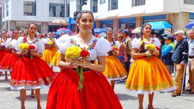 Cuenca, Ekvador - 11 Nisan 2019: Cuenca şehrinin kurulduğu gün geleneksel geçit töreni veya desfile. Güzel genç kadın halk dansçıları il Azuay (cuencana) tipik kostümleri çiçek hem il bayrağı renklerinde yapılan - kırmızı ve bağırmak