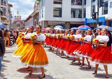 Cuenca, Ekvador - 11 Nisan 2019: Cuenca şehrinin kurulduğu gün geleneksel geçit töreni veya desfile. Güzel genç kadın halk dansçıları il Azuay (cuencana) tipik kostümleri çiçek hem il bayrağı renklerinde yapılan - kırmızı ve bağırmak