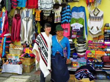 Alausi, Ekvador - 18 Şubat 2015: Turist kadın ile yerli ekvadorlu kadın-tüccar turistik kasaba Alausi, Chimborazo eyaletinde geleneksel yünlü giysi ve hediyelik eşya gösterisi yanında