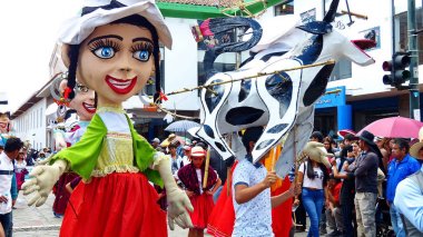 Cuenca, Ekvador - 11 Nisan 2019: Azuay eyaleti için tipik kostümlü dev mankenler ve halk dansçıları, günlük vakıf kenti Cuenca'da geleneksel geçit törenine cholas cuencanas adı verilen törene katılıyor. Genç adam 