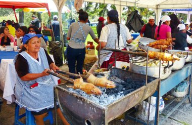 Cuenca, Ekvador - 11 Nisan 2018: Satıcı kadın cuy veya kavrulmuş kobay hazırlar - Cuenca gıda festivalinde Güney Amerika'nın geleneksel lezzetli gıda