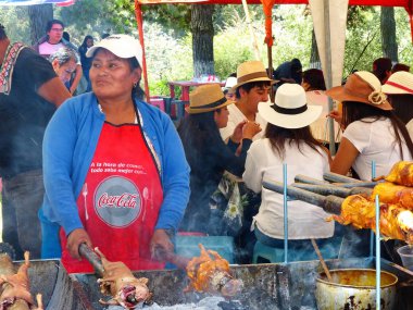 Cuenca, Ekvador - 11 Nisan 2018: Satıcı kadın Cuenca'daki yemek festivalinde satmak üzere ızgarada kavrulmuş kobay hazırlıyor. Kobay Güney Amerika'nın geleneksel ve çok popüler lezzetli gıda. Açık reşatta öğle yemeği alan bir sürü insan var.
