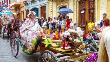 Cuenca, Ekvador - 24 Aralık 2018: Noel geçit töreni Pase del Nino Viajero. Nakış ile zengin renkli geleneksel kostüm geçit töreni için giyinmiş Kadın Noel dekorasyonu ile bir koç sürmek