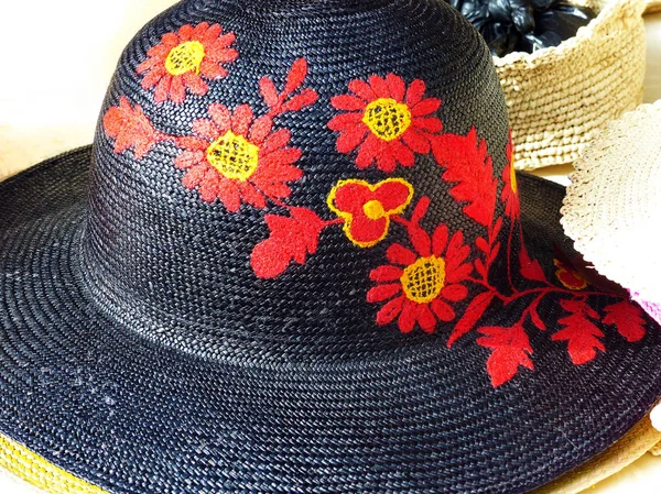 Handmade Panama Hat or Paja Toquilla hat with decorative red flowers made from straw at traditional outdoor market in Cuenca, Ecuador. Popular souvenir from South America, UNESCO cultural heritage