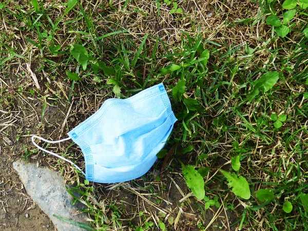 A used disposable white face mask was abandoned on the grass. Covid-19 pandemic.