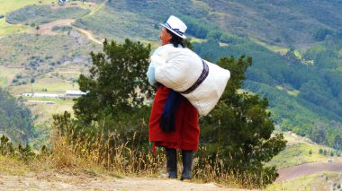 Cuenca, Ekvador - 22 Eylül 2018: Ekvador kırsal bölgesi, Azuay. Yerli köylü kadın sırtında büyük bir çanta taşıyor, Ekvador 'da ağır şeyleri taşımak için yaygın bir yol.