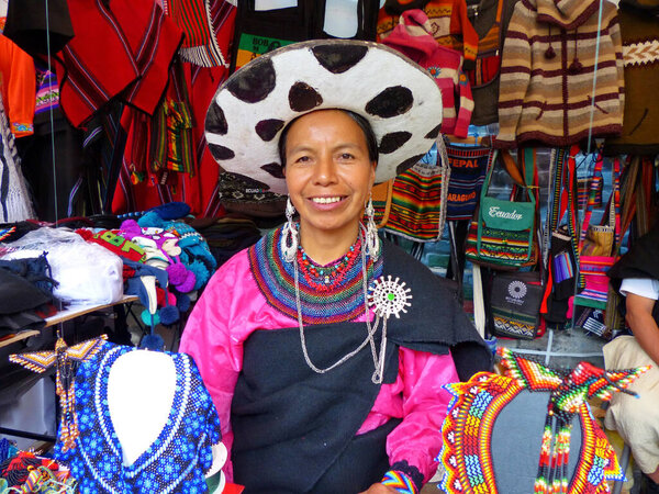 Cuenca, Ecuador - November 1, 2016: Woman of ethnic group Saraguro, province Loja, in traditional costume sells souvenirs craft at the fair on independence day of Cuenca