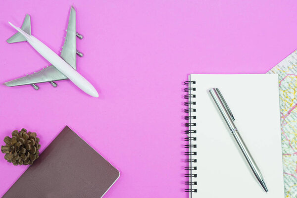 Travel concept. Blank notebook with pen and map on pink background.