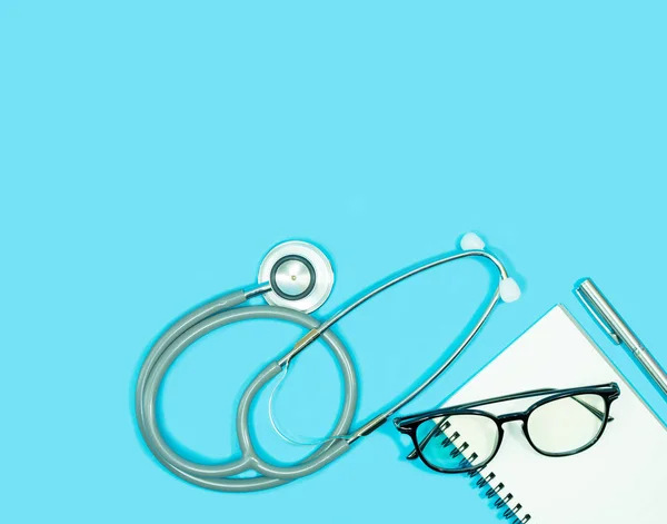 Stetoskop Ile Gözlük Üstünde Boş Defter Kalem Mavi Zemin Üzerine — Stok fotoğraf