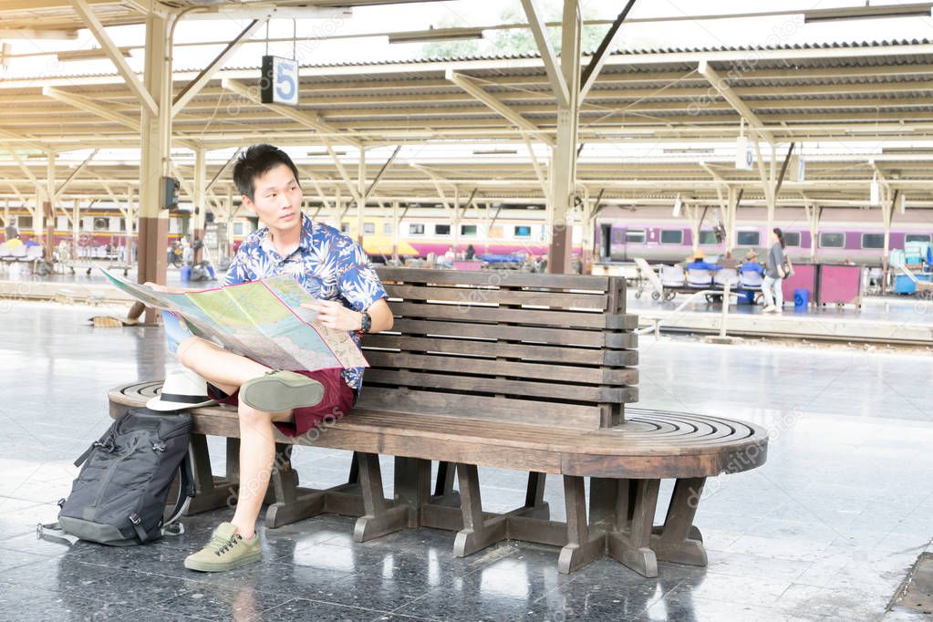 Asian traveler holding map at platform.  Travel by train concept