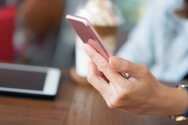 Yumuşak ışık ile kahve kafede Smartphone kullanarak ele.