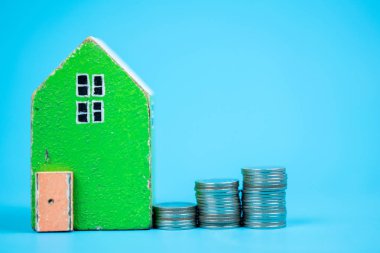 Renk arka plan üzerinde paralar ile model evi. Ev için para tasarrufu kavramları.