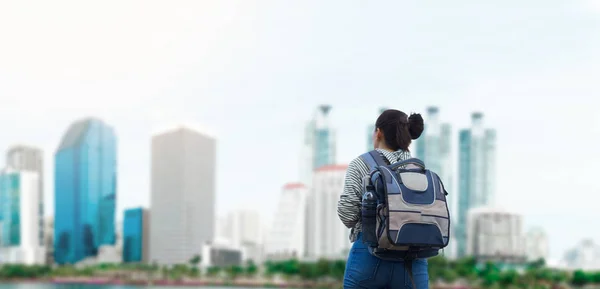 Women traveler with backpack on city background.