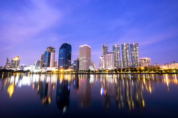 High buildings reflect the lake at night in Bangkok, Thailand.