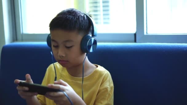 Happy Kid Jogar Jogo Com Smartphone Usando Fone Ouvido Casa — Vídeo de Stock