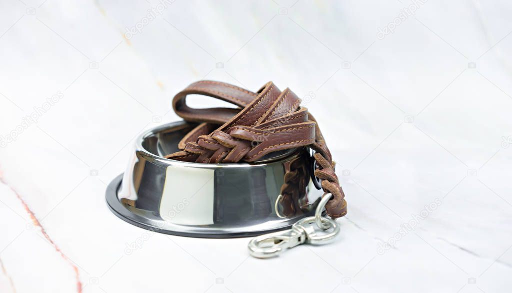 Pet supplies concept.  Pet leather leashes on stainless bowls.