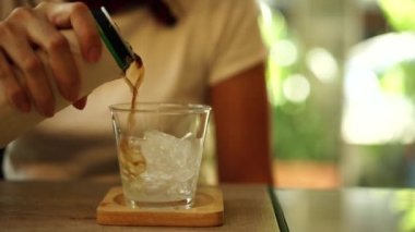 Kadın el Dökün alkolsüz içecek bir bardak buz içinde.