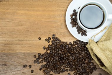 Sıcak kahve fincanı kahve çekirdekleri ile ahşap masa üzerinde kopya alanı ile.