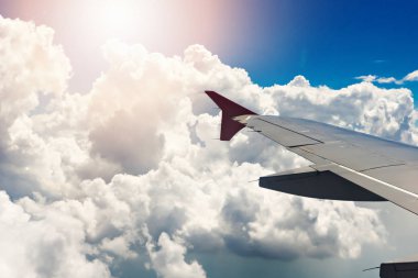 Uçak pencereden dışarı bakarak. Gökyüzü ve bulutlu arka plan içinden görünüm kanat