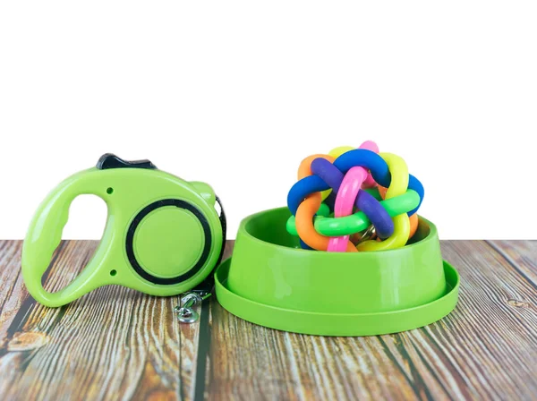 Pet supplies concept.  Pet leashes with rubber toy in bowls on wooden table and white background