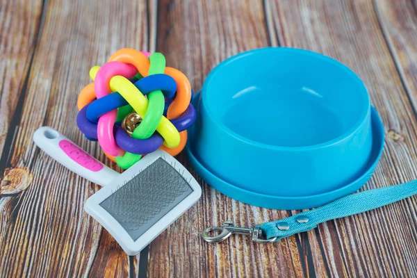 Pet accessories concept.  Pet leashes with rubber toy and bowl on wooden background.