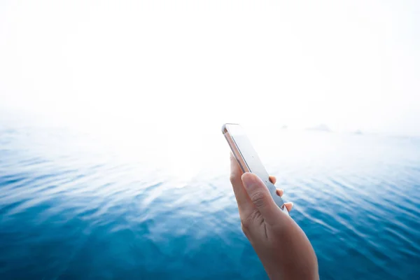 Smartphone main tenant avec fond bleu eau — Photo