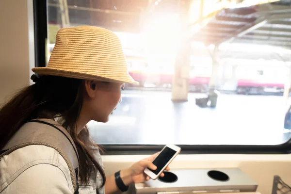 Азиатка использует смартфон для поездок на поезде — стоковое фото