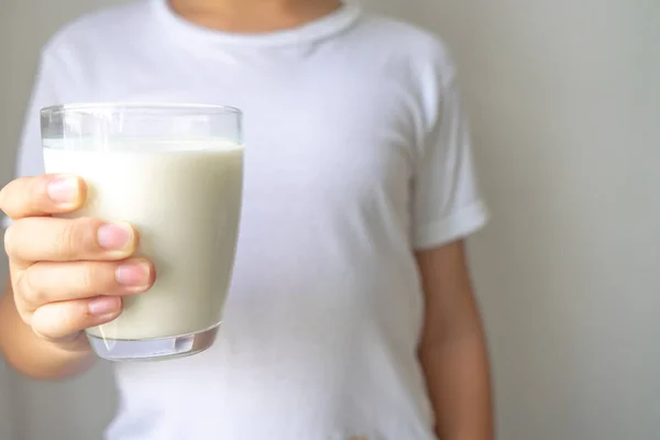 Маленький мальчик держит стакан молока для питья — стоковое фото