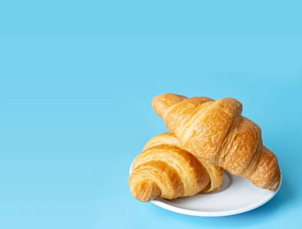 Croissant in einem weißen Teller auf farbigem Hintergrund — Stockfoto