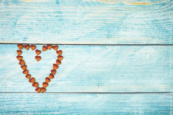 Heart shape dry food for pet on wooden background