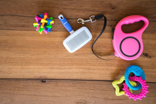 Pet leashes and rubber toy on wooden background.