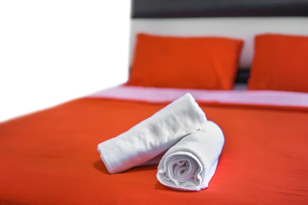 White towels roll up on bed in hotel bedroom