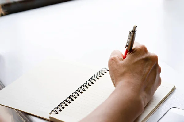 Mano sosteniendo una pluma para escribir en el cuaderno — Foto de Stock