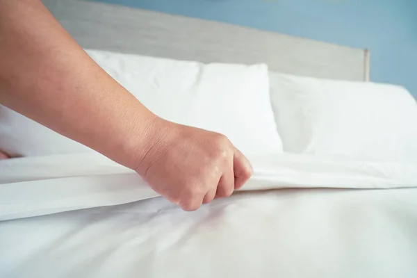 Female Hand set up white bed sheet in room hotel