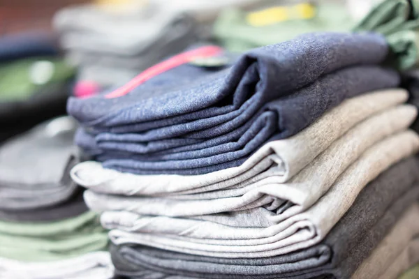Stapel T-shirts op plank in een winkel — Stockfoto