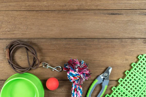 Pet leashes and rubber toy on wooden background.