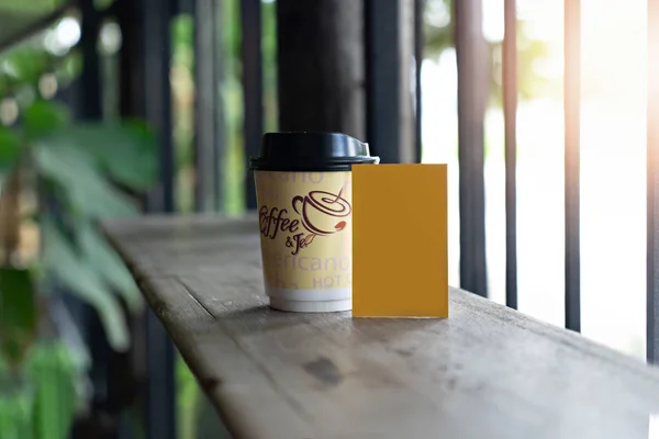 Бумажная чашка для горячего кофе с пустой карточкой на деревянном столе — стоковое фото