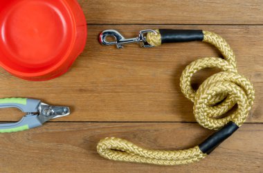 Pet leashes and plastic bowl and nail scissors on wooden table