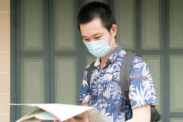 Tourist wearing health masks and holding map for travel planning